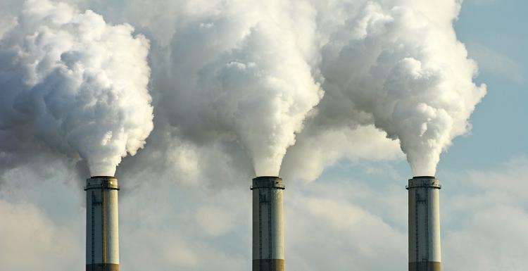 three smoke stacks with smoke billowing out